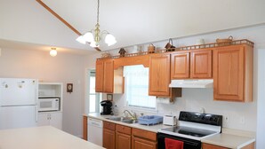 A kitchen with wooden cabinets, a white refrigerator, a microwave, a stove, and a dishwasher. - Lakefront Cottage on Lake Marion (Summerton)