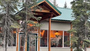 A cabin with a green door, wooden beams, and a metal roof. - Prime Kenai River Frontage with Private Lodging (Sterling)
