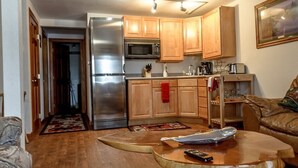A compact kitchen with wooden cabinets, a stainless steel refrigerator, and a microwave. There is a coffee maker and a toaster on the counter. - Prime Kenai River Frontage with Private Lodging (Sterling)