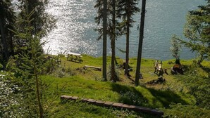 A lakeside view with picnic tables and a bench. - Prime Kenai River Frontage with Private Lodging (Sterling)