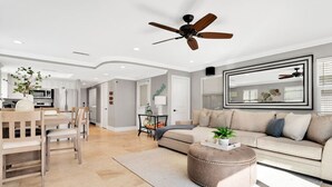 A modern living room with a sofa, ottoman, and dining area. - Steps from Beach: Stylish Getaway (Newport Beach)
