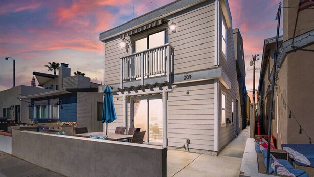A two-story house with a balcony, a barbecue area, and a patio with outdoor furniture. - Steps from Beach: Stylish Getaway (Newport Beach)