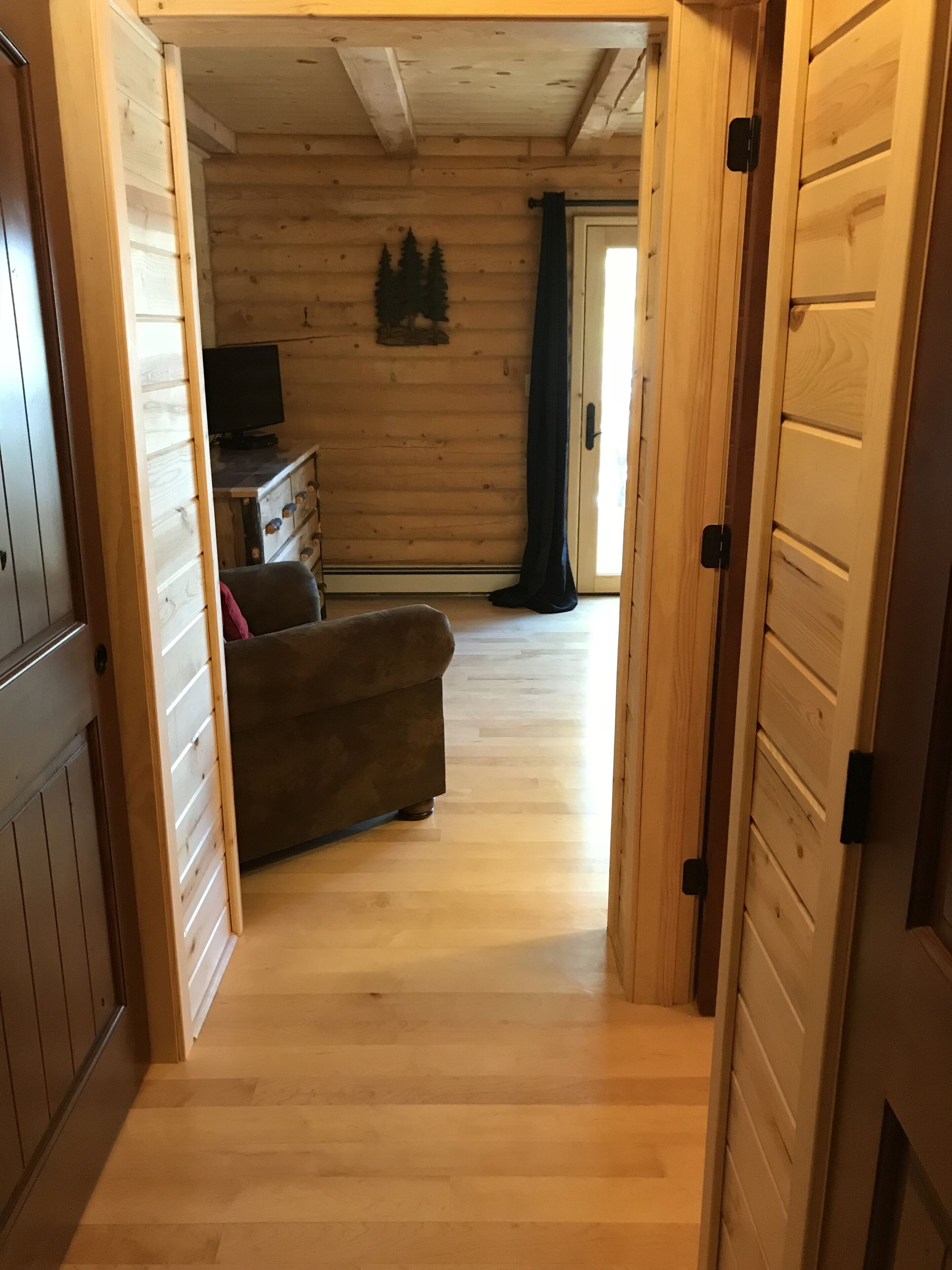 Un intérieur en bois avec un canapé, un téléviseur et un petit meuble.