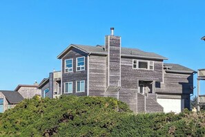 A two-story house with a prominent chimney, multiple windows, and a garage.