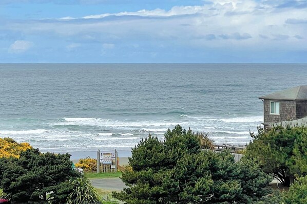 A coastal view with a wooden house and a signboard in the foreground.
