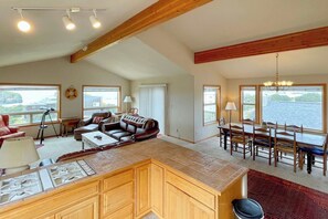 A spacious living area with a large island, a dining table, and a view of a body of water.