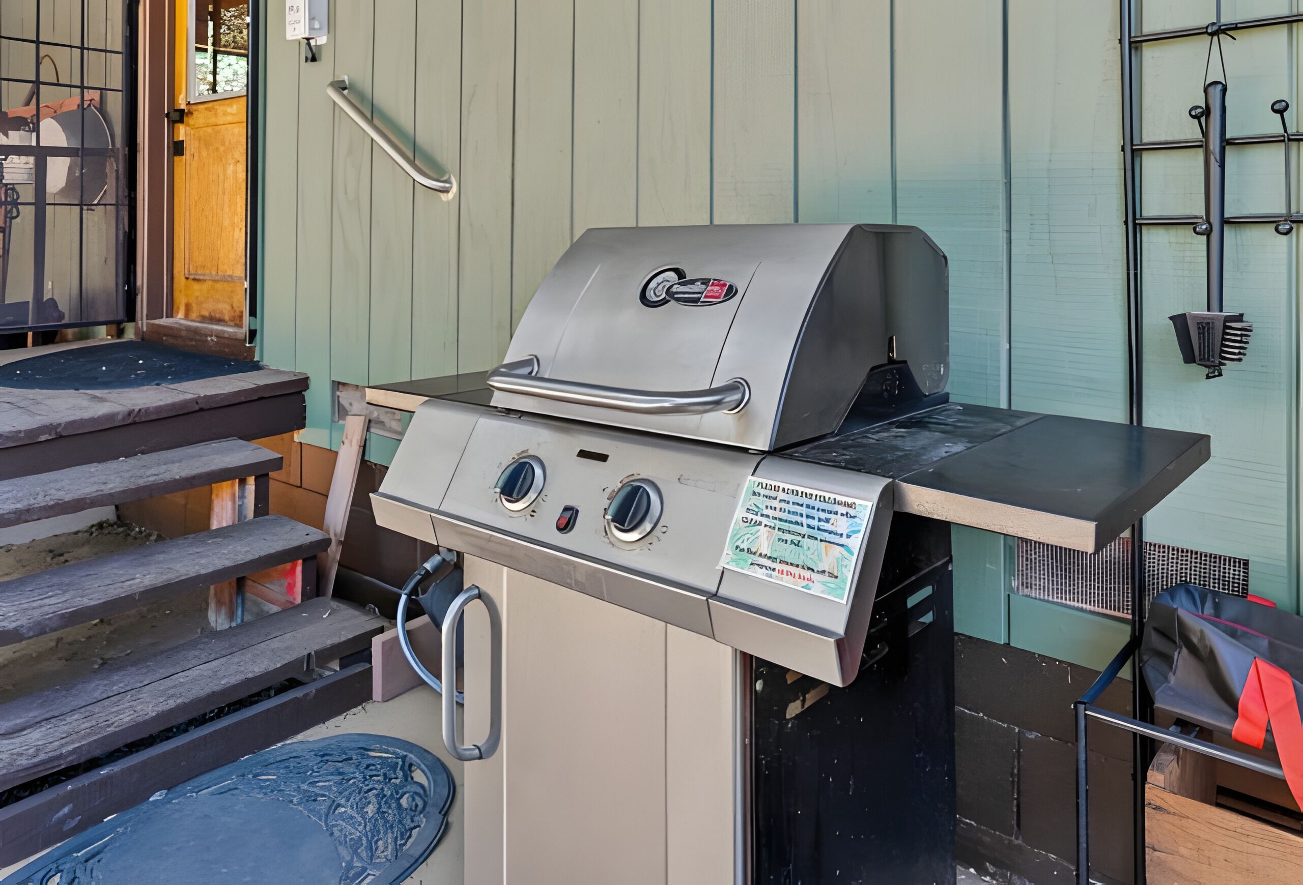 Churrasqueira com painel de controle, mangueira de gás e uma mesa de metal na frente.