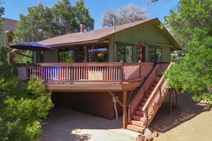 A two-story wooden building with a deck, a covered outdoor seating area, and a staircase leading to the upper level. - Pheasant Hill Cabin.  A cozy cabin and dog friendly. (Julian)