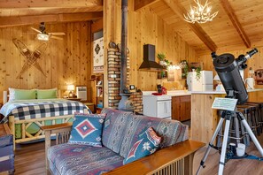 L’intérieur d’un chalet accueillant, avec un lit, un canapé et un télescope.