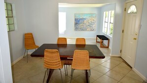 A dining room with a rectangular table and six wicker chairs. - Spacious, light-filled mid-century home in Old Town (Bay Saint Louis)