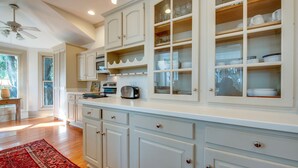 Una cucina con mobili bianchi, un tappeto rosso e una ventola a soffitto.