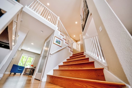 A staircase with wooden steps and white railings, leading to an upper floor.