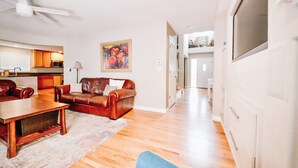 A modern living room with a brown leather sofa, a wooden coffee table, and a flat-screen TV mounted on the wall. - 8 BR -- 4 Full Baths -- Sleeps 18 - Groups OK - 20 min to Denver or Boulder HUGE (Westminster)