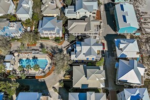 An aerial view of a residential area with multiple houses, a swimming pool, and a small parking area.