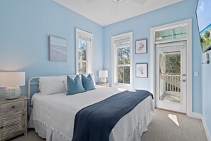 A bedroom with a bed, bedside tables, and a view of the outdoors through a door.