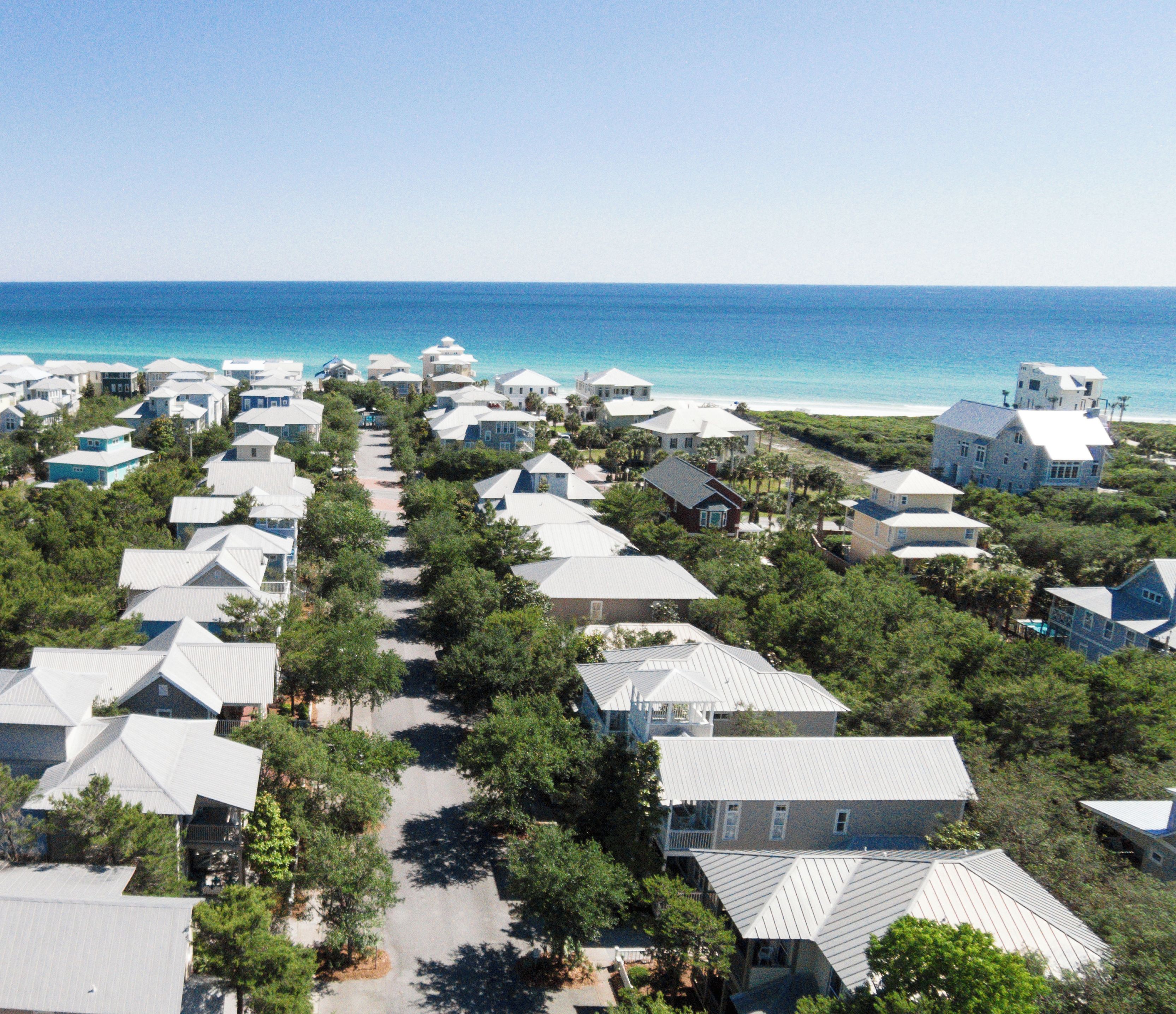 A coastal residential area with houses arranged in rows along a street, leading to the beach.