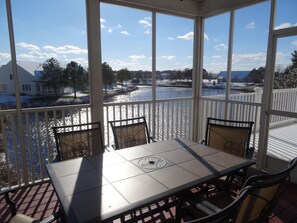 A covered outdoor area with a table and chairs, overlooking a body of water and a snow-covered landscape. - Large Luxury Villa Bethany Beach,  Golf/Tennis Resort, ammenties, beach shuttle (Ocean View)
