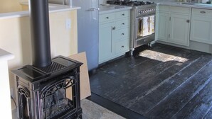 A kitchen with a black stove, white cabinets, and a skylight. - Historic 1887 Carriage House Located On Landmark Property (Santa Cruz)
