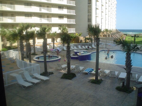 A resort pool area with multiple pools, lounge chairs, and palm trees. - Destin Home Away From Home (Destin)