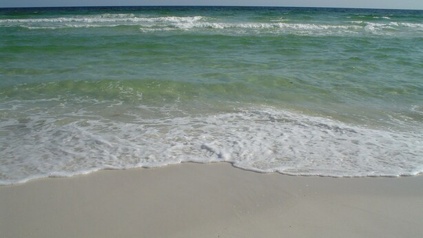 Una playa con olas suaves lamiendo la orilla.