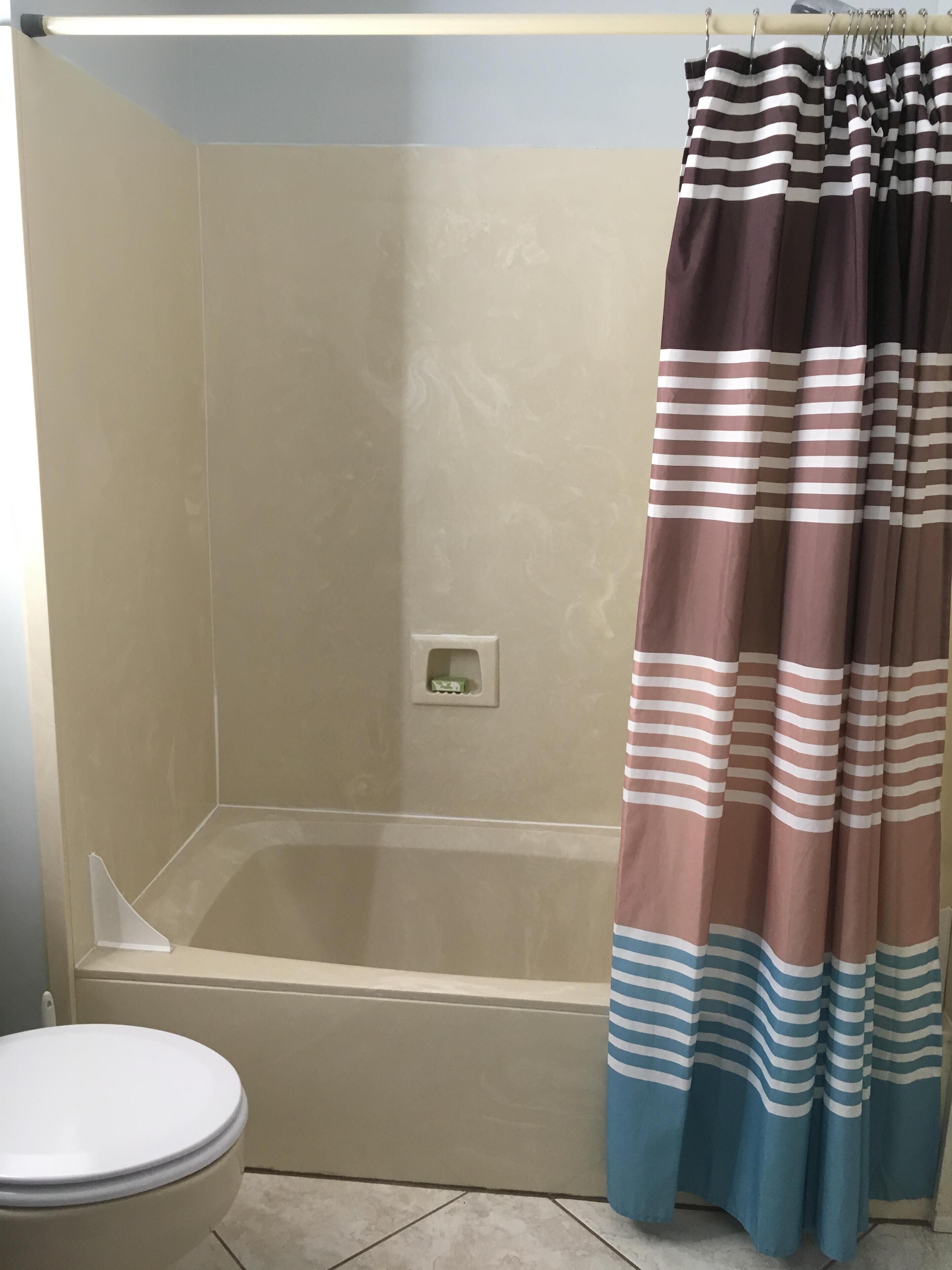 A bathroom with a bathtub, a toilet, and a shower curtain.