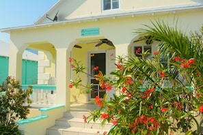 A two-story building with a sign reading "Harbour House." There are steps leading to the entrance, and the building is surrounded by greenery and red flowers. - Waterfront Cottage in Spanish Wells' protected harbor (Spanish Wells)