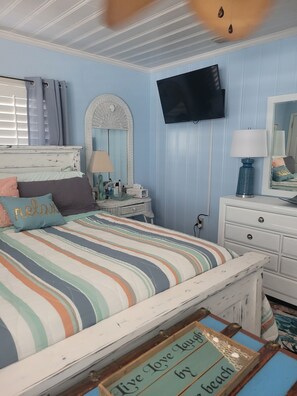 A bedroom with a bed, dresser, mirror, television, and a sign on the floor. - Visit 'Derondo Delight' Beach House - Just Steps from the Gulf (Panama City Beach)