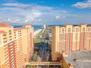 Ein Hochhaus-Hotel mit mehreren Balkonen, Blick auf den Strand und einem Parkplatz.