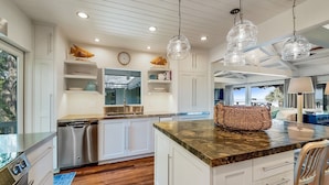 Una cocina moderna con armarios blancos, una isla central e iluminación colgante.