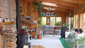A cozy cabin interior with a stone fireplace, wooden walls, a sofa, and a ceiling fan. - 1-2 Family Perfection:  Location + Views + Ammenities = Value (West Dover)