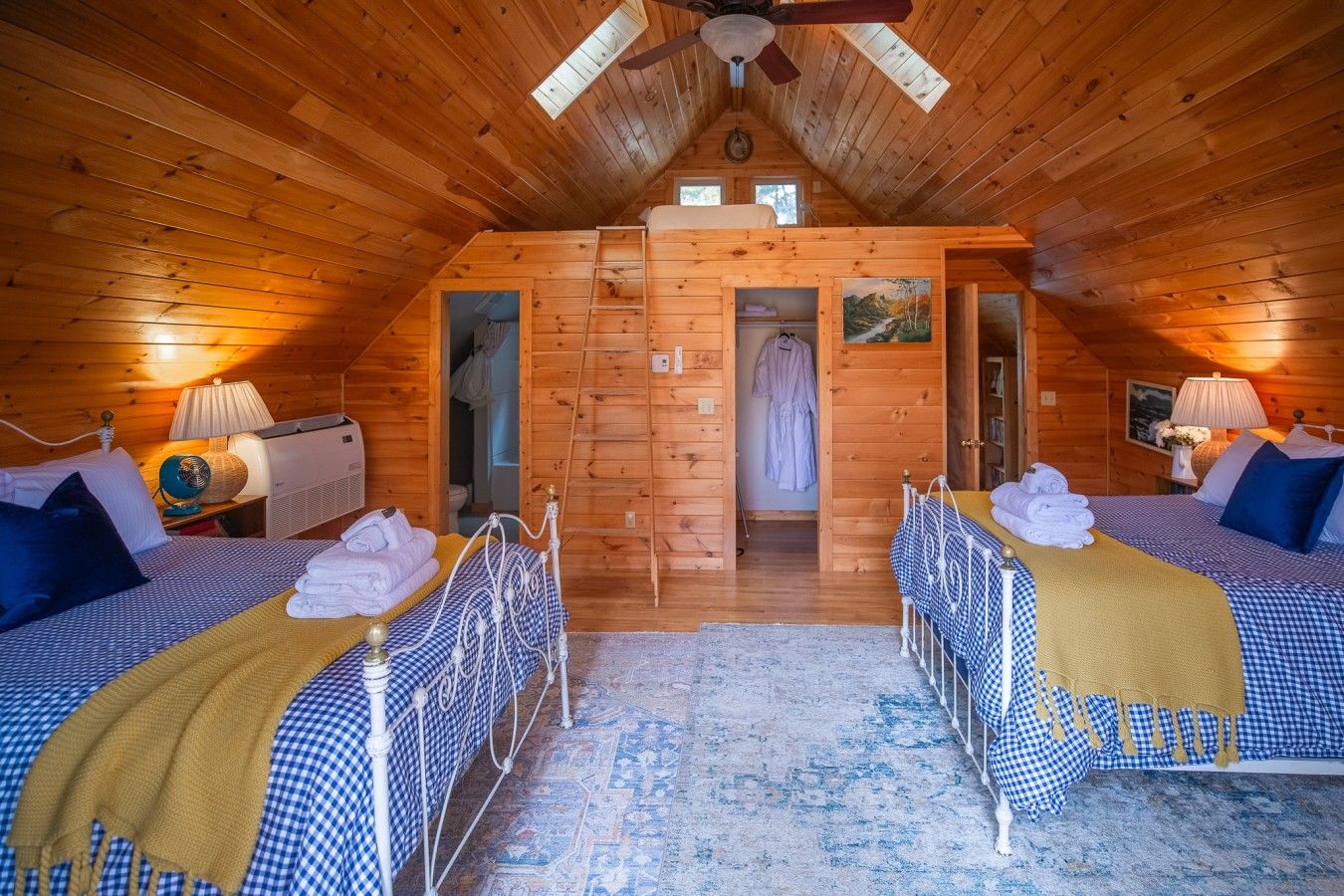 Upstairs bedroom with two full beds and a ladder up to a sleeping loft with a twin bed. It opens onto a balcony with a café table and chairs, perfect for morning coffee.