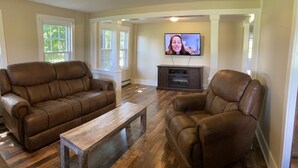A living room with two brown leather sofas, a wooden coffee table, and a television on the wall. - Finger lakes region outdoor getaway (Lafayette)