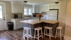 A kitchen with a wooden island, white bar stools, and a vase of sunflowers. - Finger lakes region outdoor getaway (Lafayette)