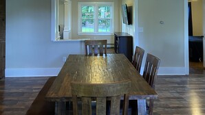 A dining area with a wooden table and chairs, a chandelier, and a view of the outdoors through a window. - Finger lakes region outdoor getaway (Lafayette)