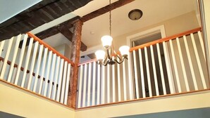 A multi-level interior with a wooden staircase, white railings, and a chandelier. - Finger lakes region outdoor getaway (Lafayette)