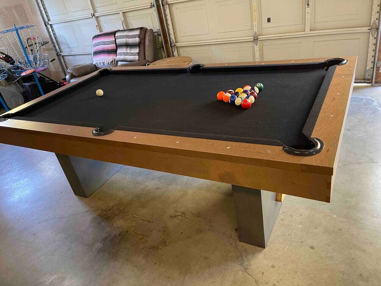 Mesa de bilhar com uma bola e taco em uma garagem.