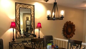 A dining area with a round table, chairs, and two lamps.