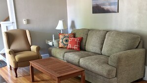 Una sala de estar con sofá, sillón y una mesa de centro de madera.