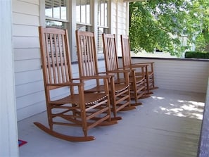 Eine Veranda mit vier hölzernen Schaukelstühlen.