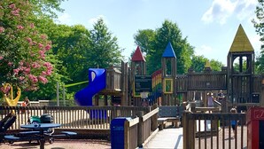 A playground with a slide, climbing structures, and picnic tables.