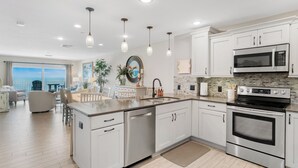 A modern kitchen with white cabinetry, stainless steel appliances, and pendant lighting.