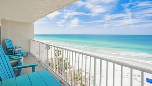 A balcony with turquoise chairs and a view of the ocean.
