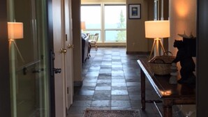 A hallway with a patterned rug, a table with a lamp, and a statue. - Unparalleled 180-degree Views of Lake Superior, 400 feet above the water! (Two Harbors)