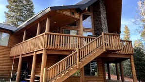 A log cabin with a wooden staircase leading to a balcony. - Large Cabin for Family & Friends to Enjoy - Close to many outdoor activities (Duck Creek Village)