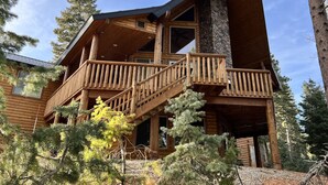 A log cabin with a balcony and a stone chimney. - Large Cabin for Family & Friends to Enjoy - Close to many outdoor activities (Duck Creek Village)