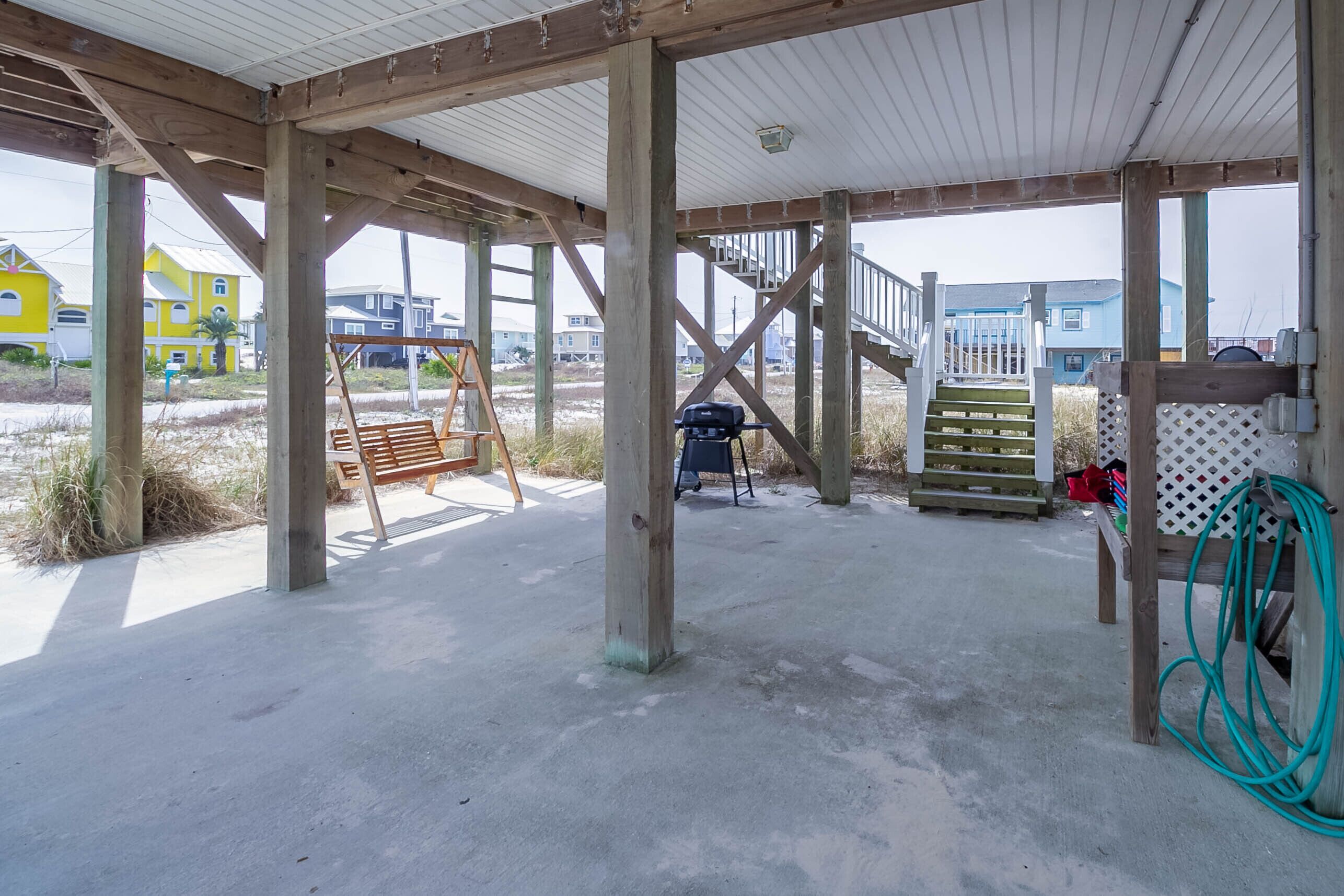 Una obra en construcción con vigas de madera y suelo de concreto, un banco de madera, una escalera y una escalera que sube a un nivel superior.