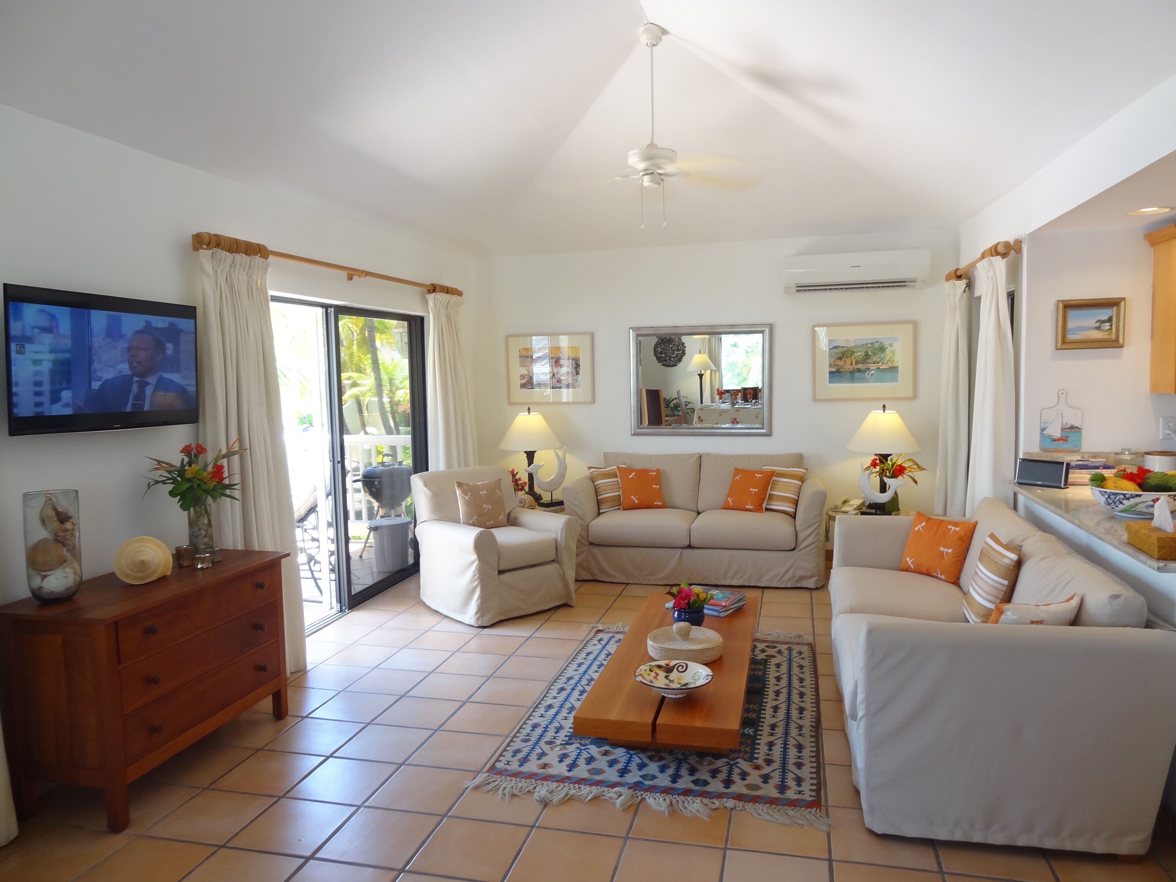 A spacious living room with a sofa set, a coffee table, a TV, and a sliding glass door leading to a balcony.