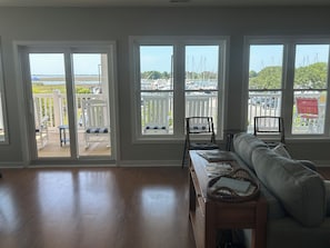 A living room with a sofa, a wooden table, and a view of a marina through large windows.
