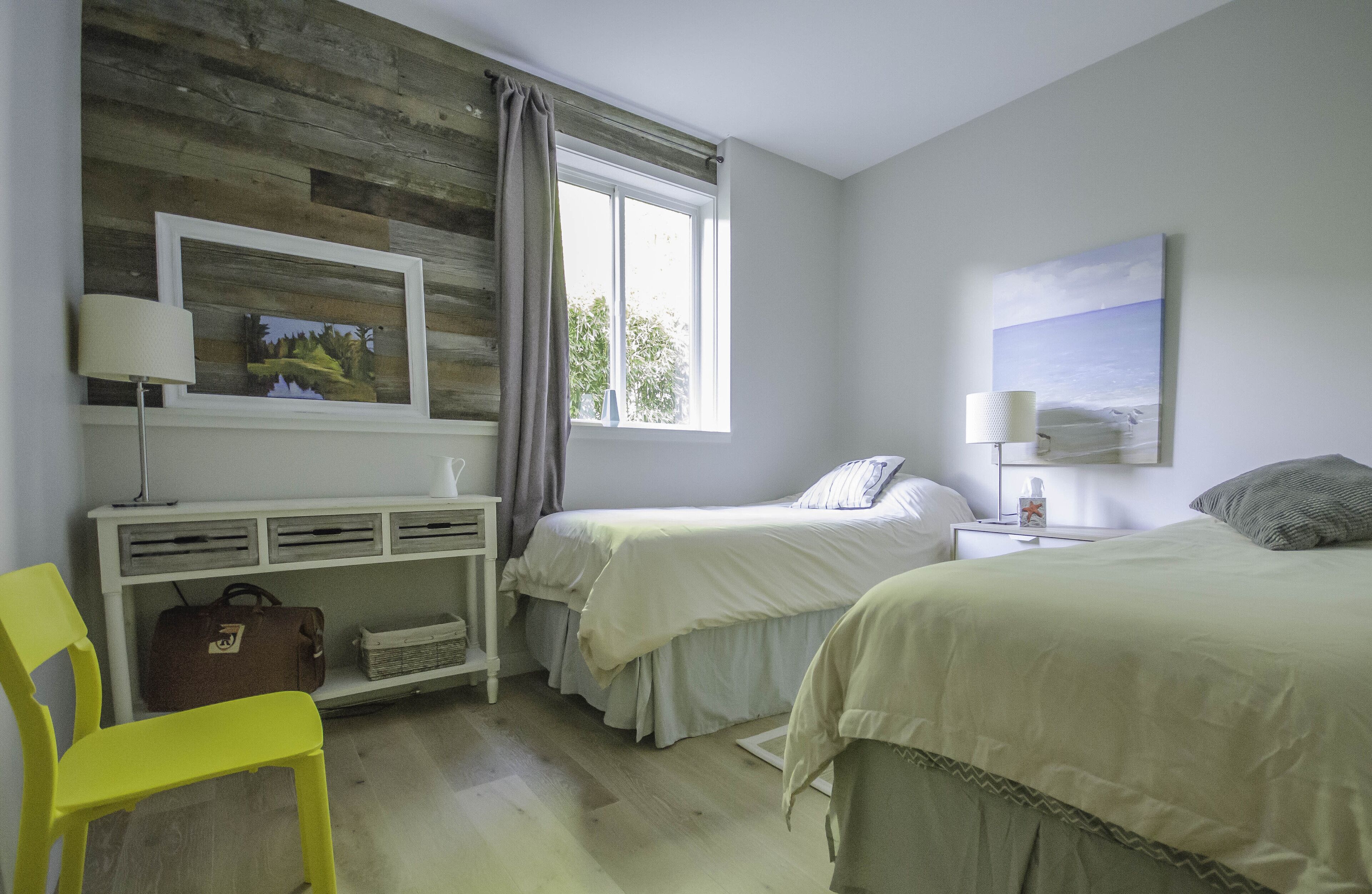 A bedroom with two beds, a desk, a chair, and a window with curtains.