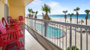 Ein Balkon mit roten Stühlen, einem Pool und Blick auf den Strand.